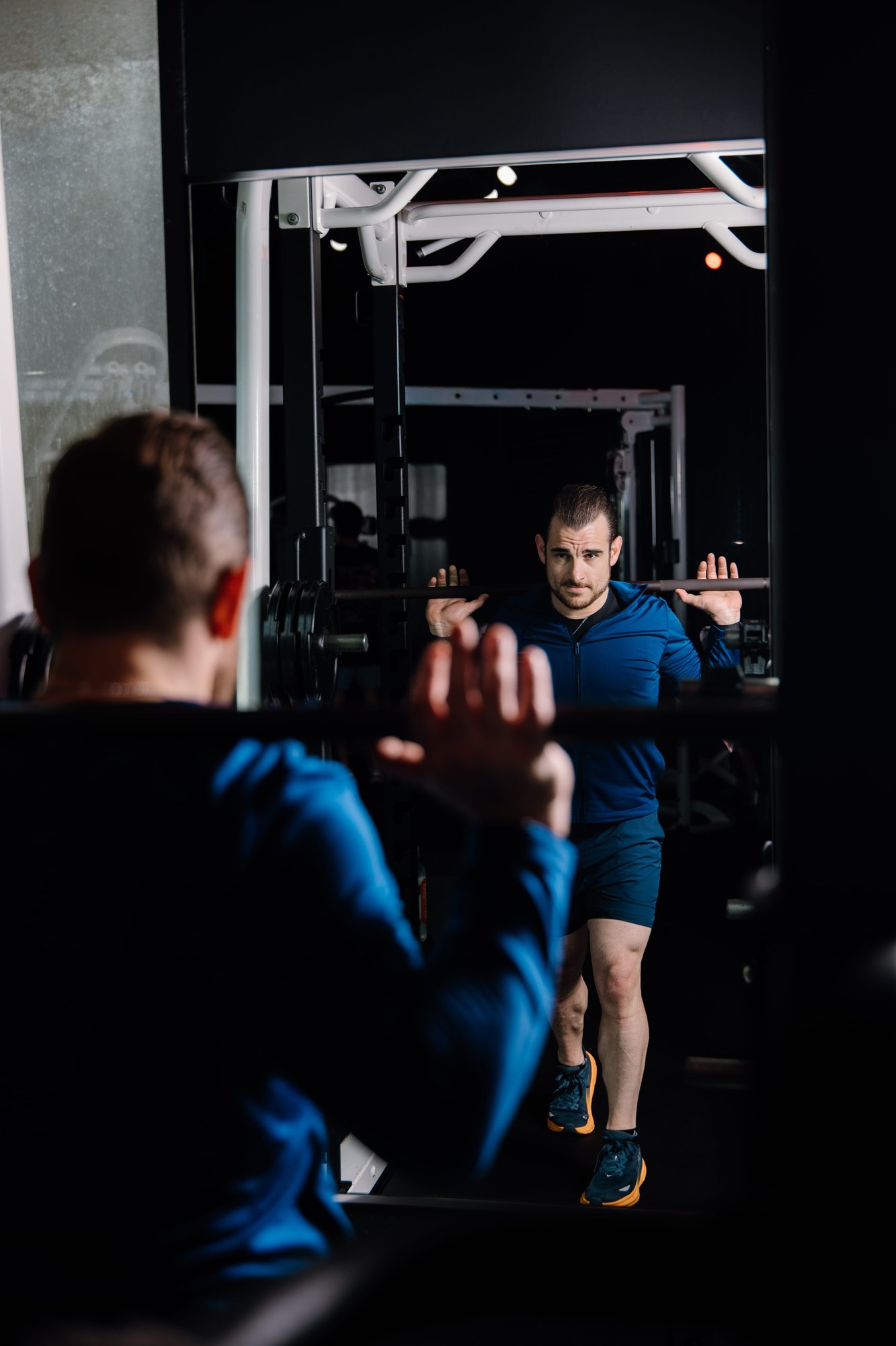 Jonathan Forstall setting up a front squat in a dimly lit gym